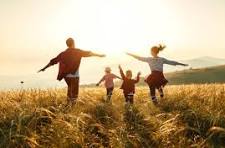 A family running through a wheat field at sunset